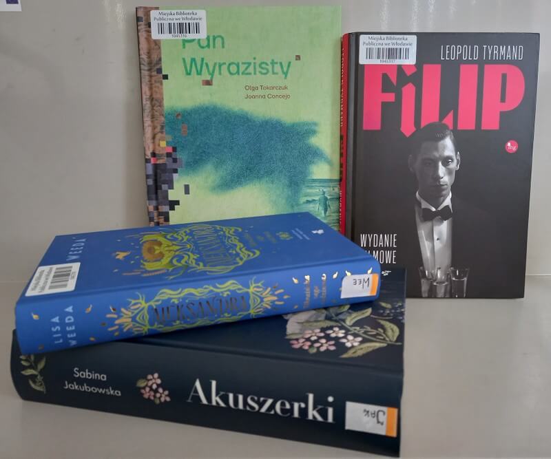 Dwie książki stojące, widoczne okładki: Olga Tokarczuk, Joanna Concejo: Pan Wyrazisty, Leopold Tyrmand: Filip; dwie książki leżące, widoczne grzbiety.