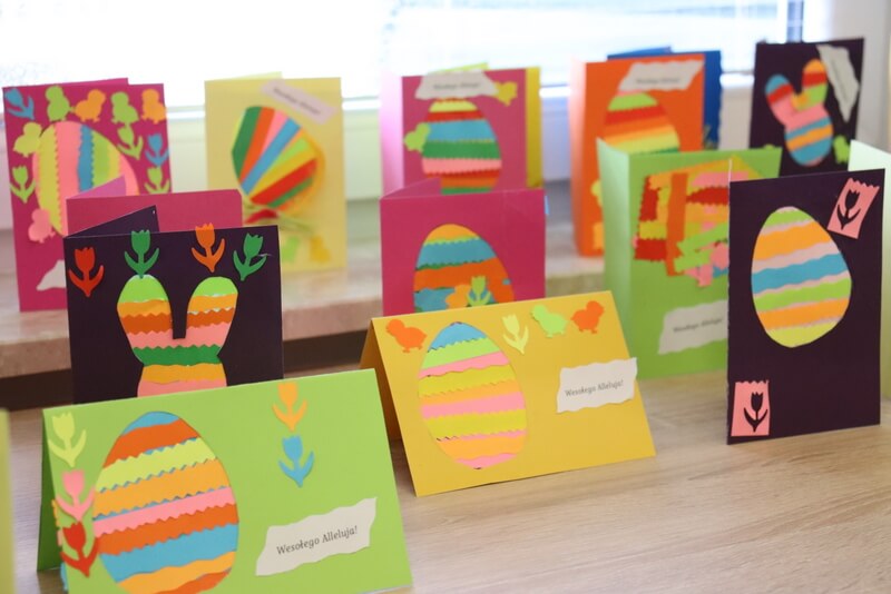 Na stole stoją wyeksponowane kolorowe kartki przygotowane przez dzieci. Kartki z motywem pisanki i zajączka. 