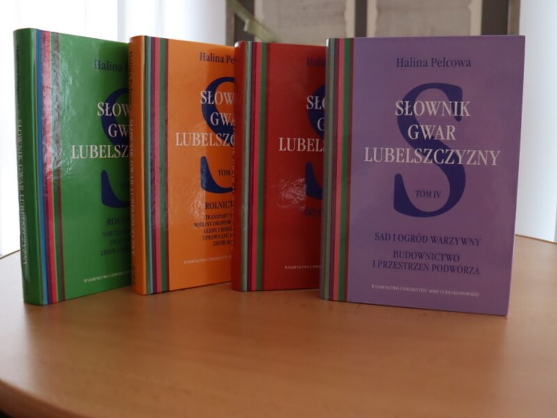 Cztery tomy Słownika gwar Lubelszczyzny stojące na stole. 