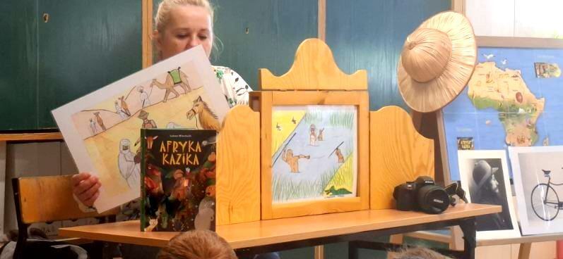 Prowadząca czyta dzieciom bajkę obrazkową za pomocą teatrzyku kamishibai.
